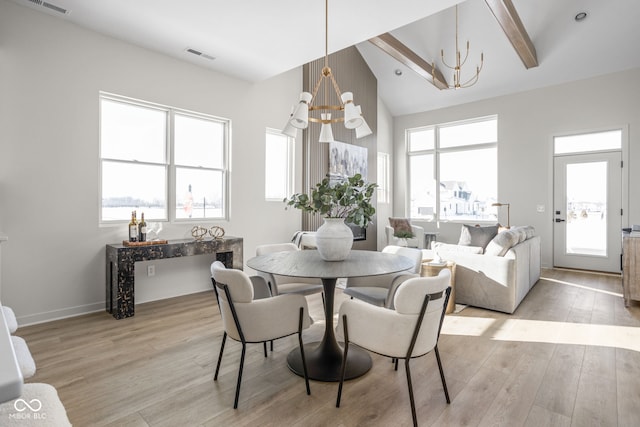 dining area with plenty of natural light, light hardwood / wood-style flooring, beamed ceiling, and an inviting chandelier