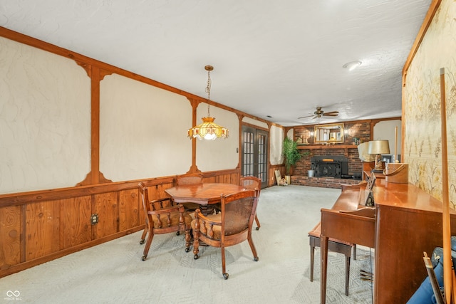 carpeted dining space featuring a textured ceiling, wooden walls, ceiling fan, and ornamental molding