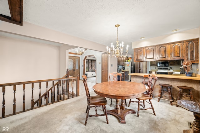 dining room with light colored carpet, a textured ceiling, and a chandelier