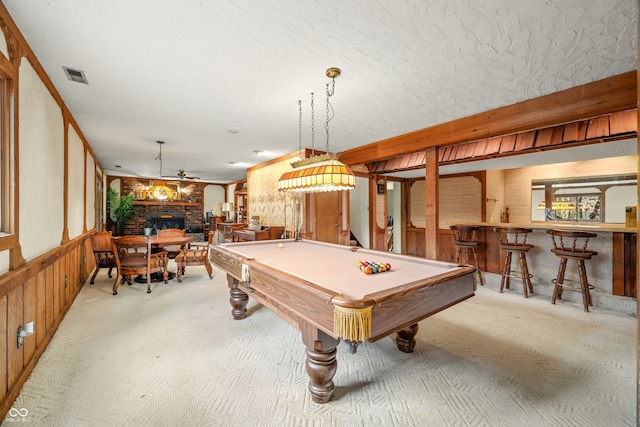 game room featuring light carpet, billiards, wooden walls, indoor bar, and a fireplace