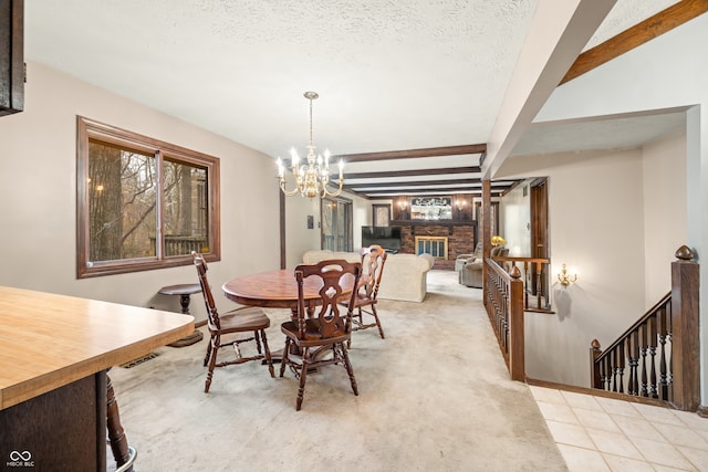 dining room featuring a brick fireplace, a textured ceiling, beam ceiling, light colored carpet, and a chandelier