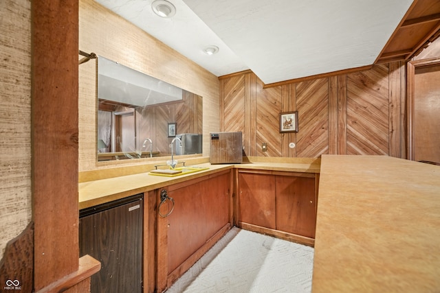 bar featuring light carpet, stainless steel fridge, wooden walls, and sink