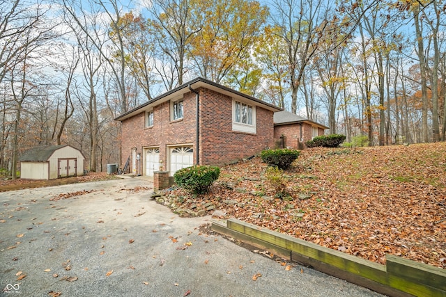 view of side of home featuring central air condition unit, a storage shed, and a garage