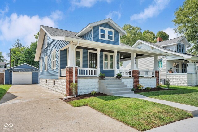 bungalow-style house featuring a front yard, a garage, an outbuilding, and a porch