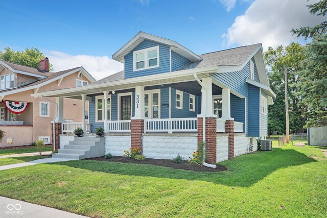 bungalow-style house featuring a front lawn, cooling unit, and covered porch