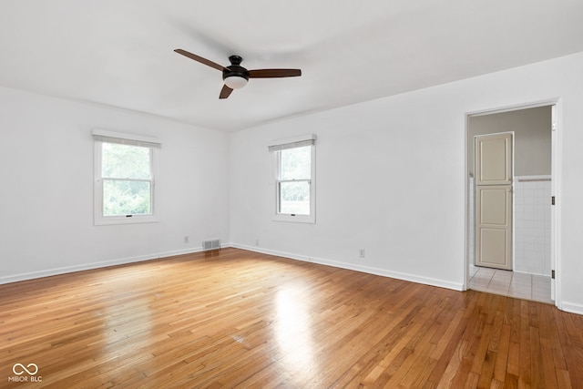 spare room featuring light hardwood / wood-style floors, ceiling fan, and a healthy amount of sunlight