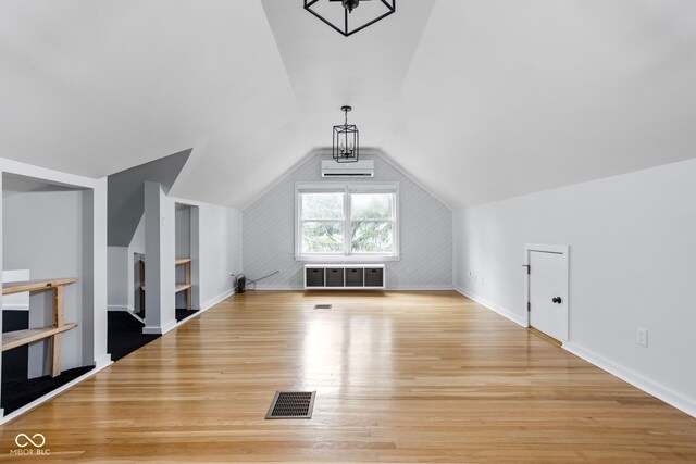 bonus room featuring built in shelves, light wood-type flooring, lofted ceiling, and a wall mounted AC