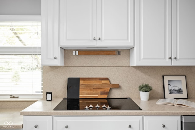 interior space featuring black electric cooktop, white cabinetry, and tasteful backsplash