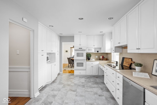 kitchen featuring white cabinetry, black electric cooktop, double oven, dishwasher, and light wood-type flooring