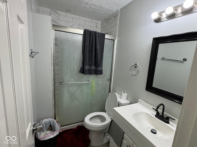 bathroom with vanity, toilet, a shower with shower door, and a textured ceiling