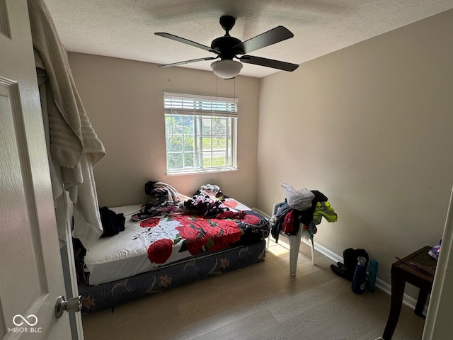 bedroom with ceiling fan, a textured ceiling, and light hardwood / wood-style flooring