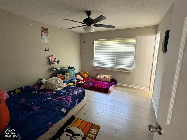 bedroom featuring ceiling fan, a textured ceiling, and light wood-type flooring