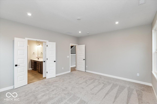 unfurnished bedroom featuring light colored carpet and ensuite bath