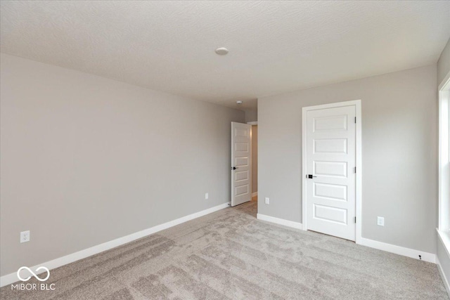 empty room featuring a textured ceiling and light carpet