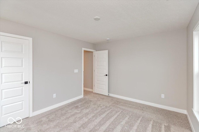 unfurnished room with light colored carpet and a textured ceiling