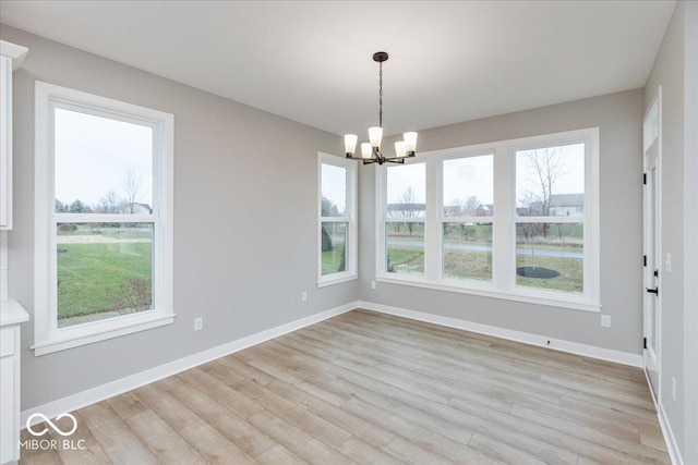 unfurnished dining area featuring light hardwood / wood-style floors, an inviting chandelier, and a wealth of natural light