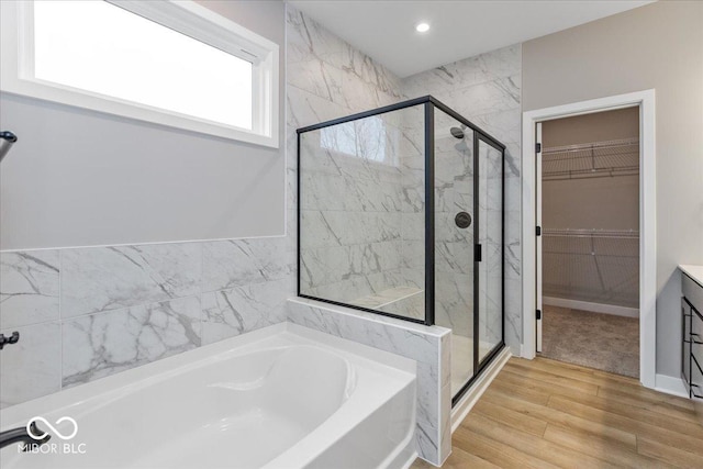 bathroom with wood-type flooring and shower with separate bathtub