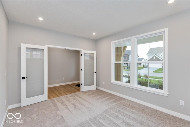 unfurnished bedroom with light carpet and french doors