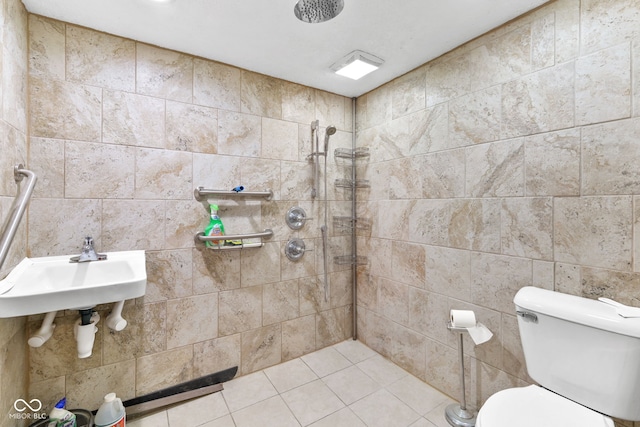 bathroom featuring tile walls, toilet, tile patterned flooring, a tile shower, and a sink