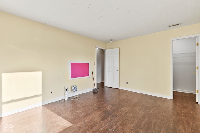 unfurnished bedroom featuring hardwood / wood-style floors, a spacious closet, and a closet