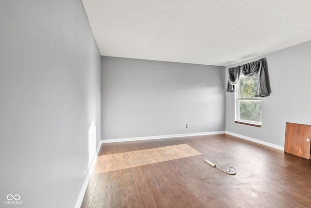 spare room with dark wood-style floors and baseboards