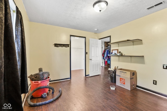 miscellaneous room with dark wood-style floors, a textured ceiling, visible vents, and baseboards