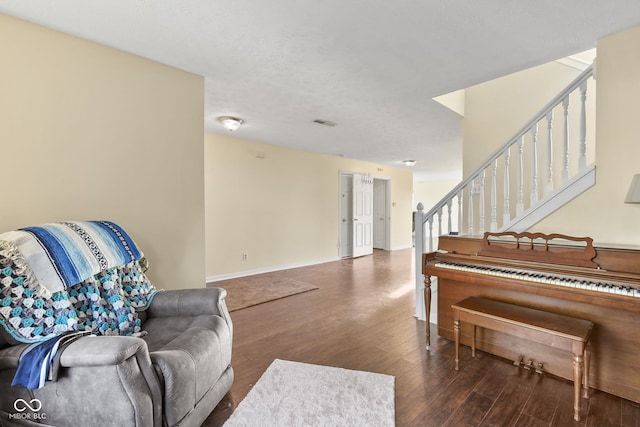 sitting room with dark wood-style floors, stairway, visible vents, and baseboards