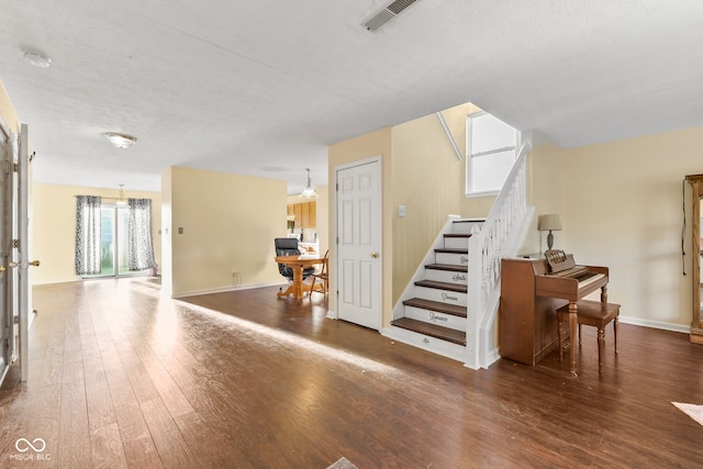 interior space featuring baseboards, visible vents, a textured ceiling, and hardwood / wood-style floors