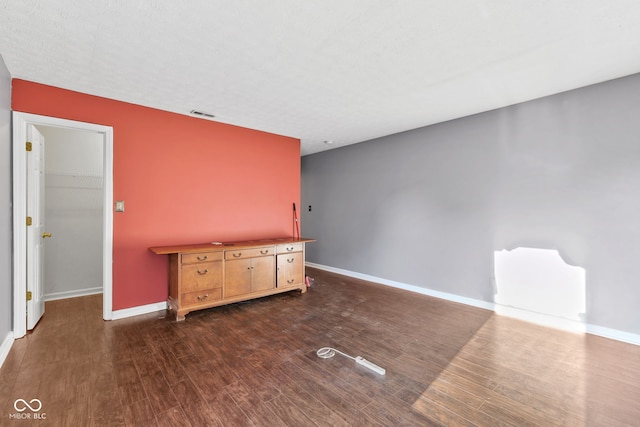 unfurnished room with dark wood finished floors, visible vents, and baseboards