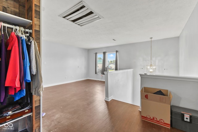 unfurnished room featuring hardwood / wood-style flooring, a textured ceiling, and a chandelier