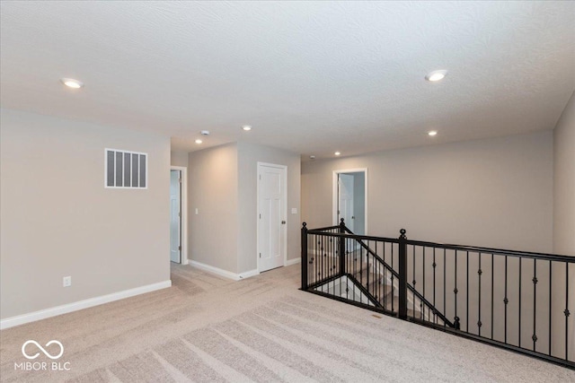 empty room featuring light carpet and a textured ceiling