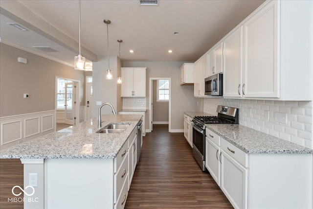 kitchen with stainless steel appliances, sink, white cabinets, and a kitchen island with sink