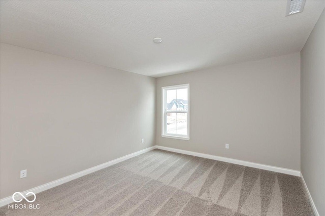 spare room featuring carpet flooring and a textured ceiling