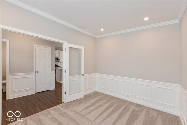 unfurnished room with ornamental molding and dark carpet