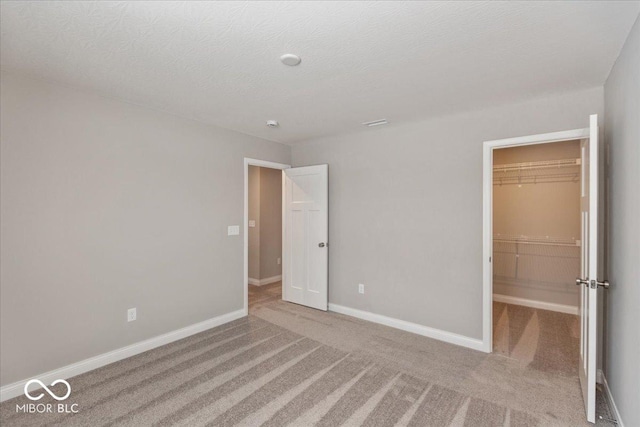 unfurnished bedroom featuring a spacious closet, carpet floors, a closet, and a textured ceiling