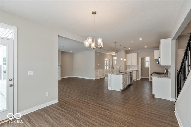 kitchen featuring decorative light fixtures, sink, white cabinets, dark hardwood / wood-style flooring, and a center island with sink