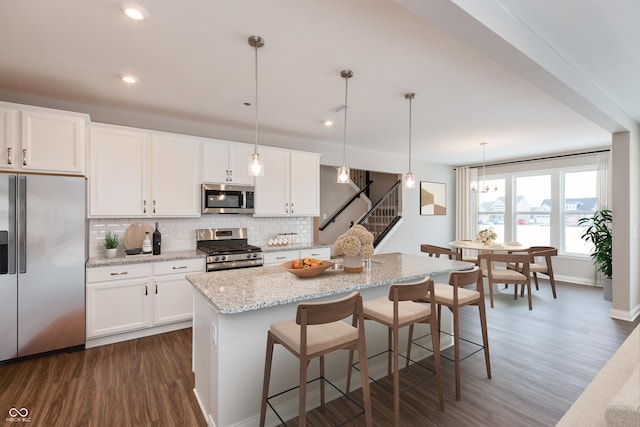 kitchen featuring white cabinetry, appliances with stainless steel finishes, and decorative light fixtures