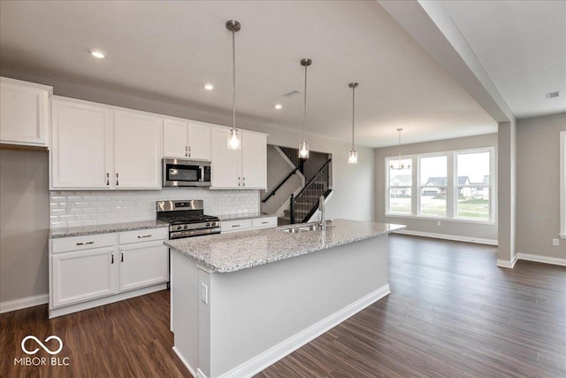 kitchen featuring dark wood finished floors, stainless steel appliances, backsplash, a sink, and white cabinetry