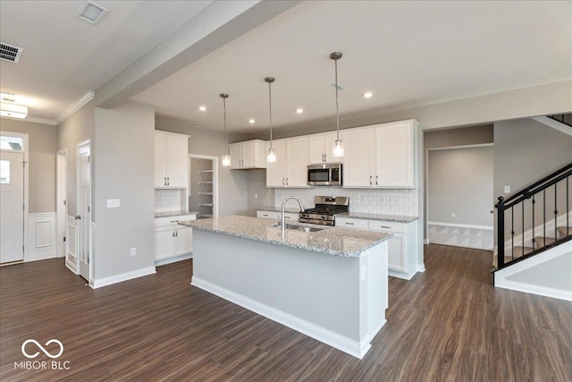 kitchen with dark wood finished floors, white cabinetry, stainless steel appliances, and a sink