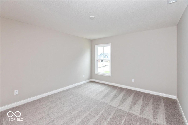 carpeted empty room featuring a textured ceiling and baseboards