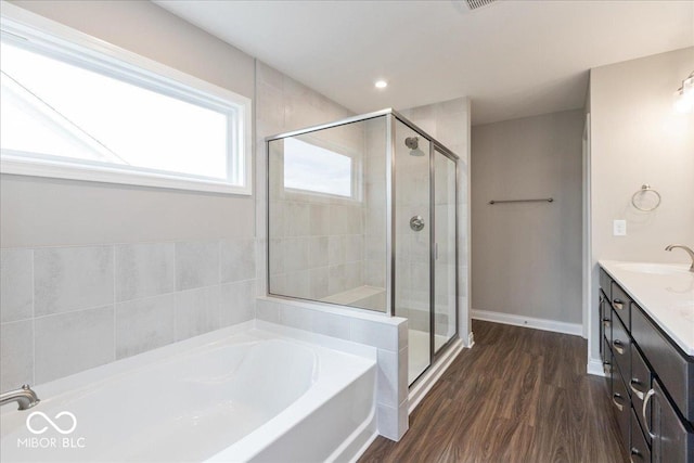 bathroom featuring a shower stall, a garden tub, vanity, and wood finished floors