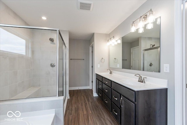 bathroom featuring a shower stall, wood finished floors, a sink, and visible vents