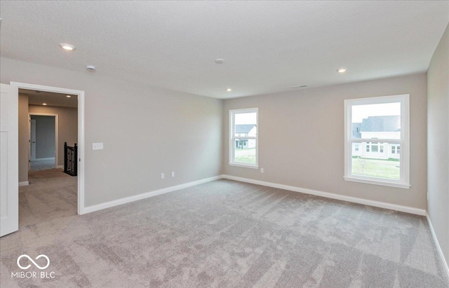 carpeted spare room featuring baseboards and recessed lighting