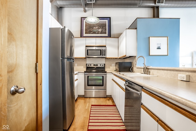 kitchen with white cabinets, appliances with stainless steel finishes, light hardwood / wood-style floors, and sink