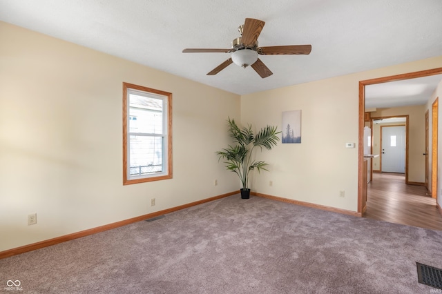 spare room with ceiling fan, carpet, visible vents, and baseboards