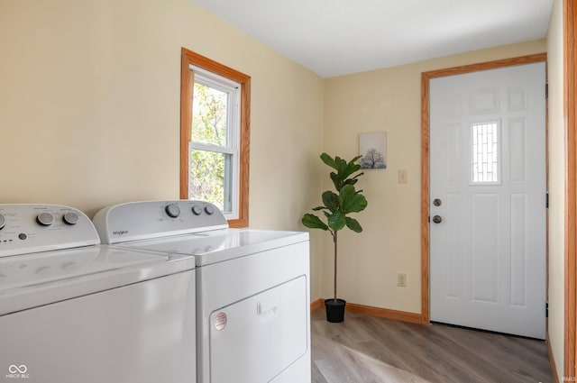 washroom with baseboards, laundry area, washer and clothes dryer, and light wood-style floors