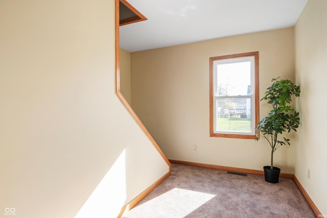 spare room with light carpet, visible vents, and baseboards