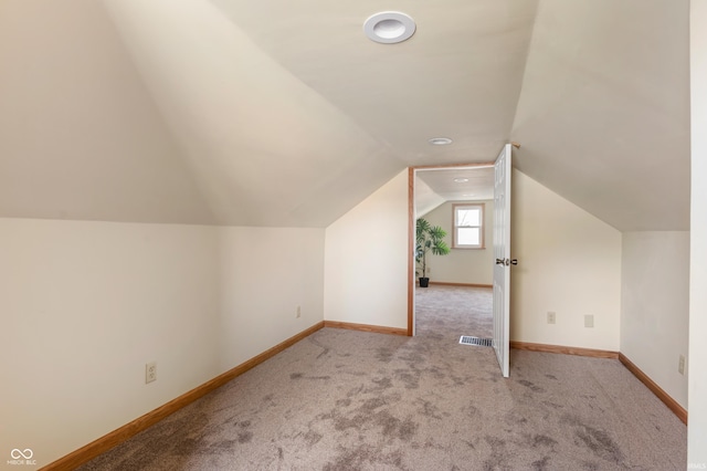 bonus room featuring baseboards, visible vents, vaulted ceiling, and light colored carpet