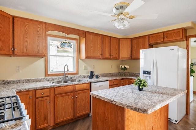 kitchen with a center island, brown cabinets, a sink, ceiling fan, and white appliances