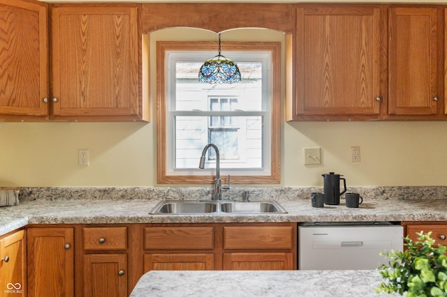 kitchen featuring dishwasher, brown cabinetry, a sink, and pendant lighting